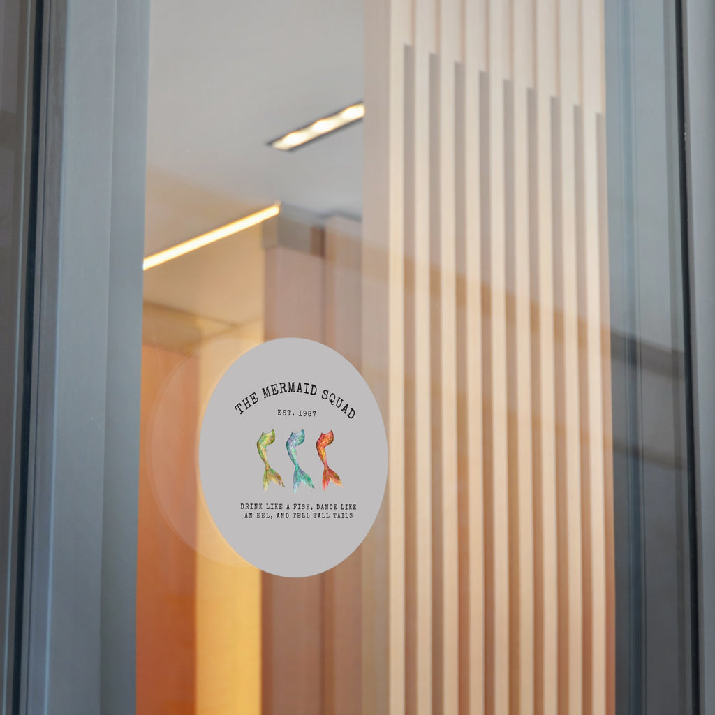 The Mermaid Squad round vinyl sticker in grey, shown on a glass door, alternate view