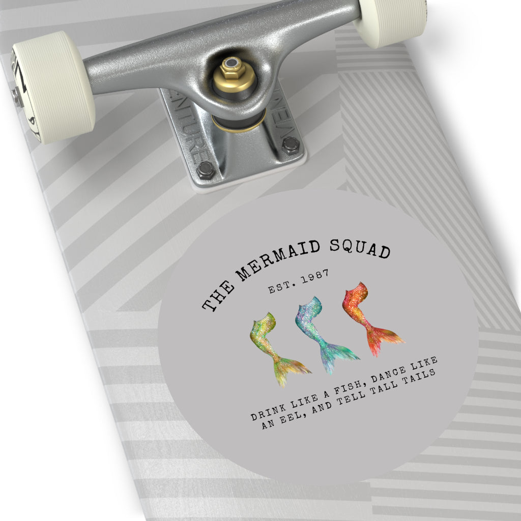 The Mermaid Squad round vinyl sticker in grey, shown on a longboard, alternate view