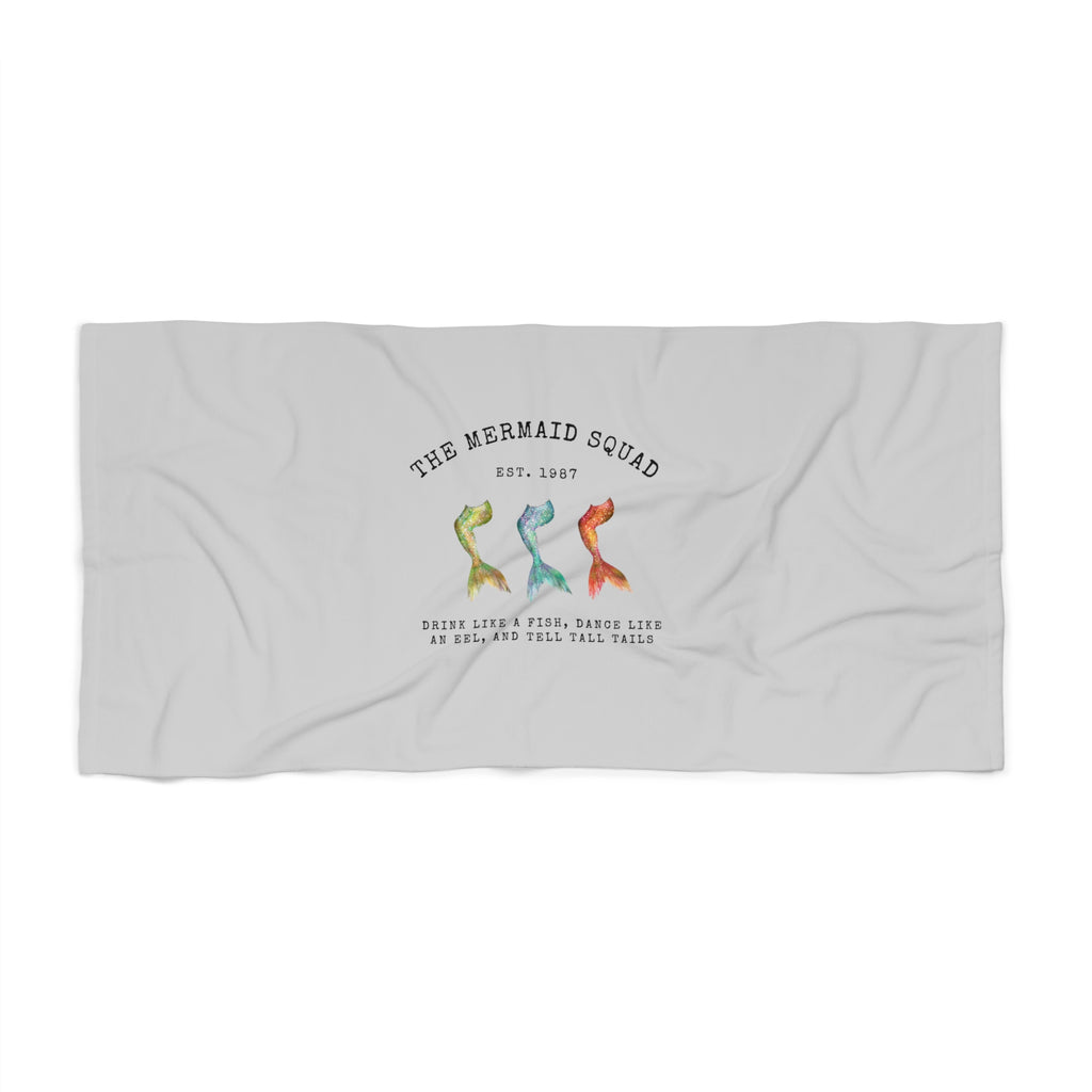 The Mermaid Squad beach towel, flat lay view with three colorful mermaid tails design