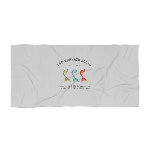 The Mermaid Squad beach towel, flat lay view with three colorful mermaid tails design