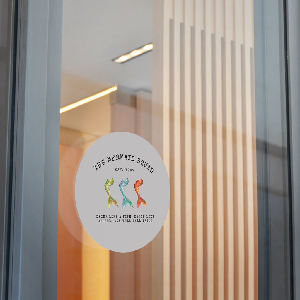 The Mermaid Squad round vinyl sticker in grey, shown on a glass door, alternate view