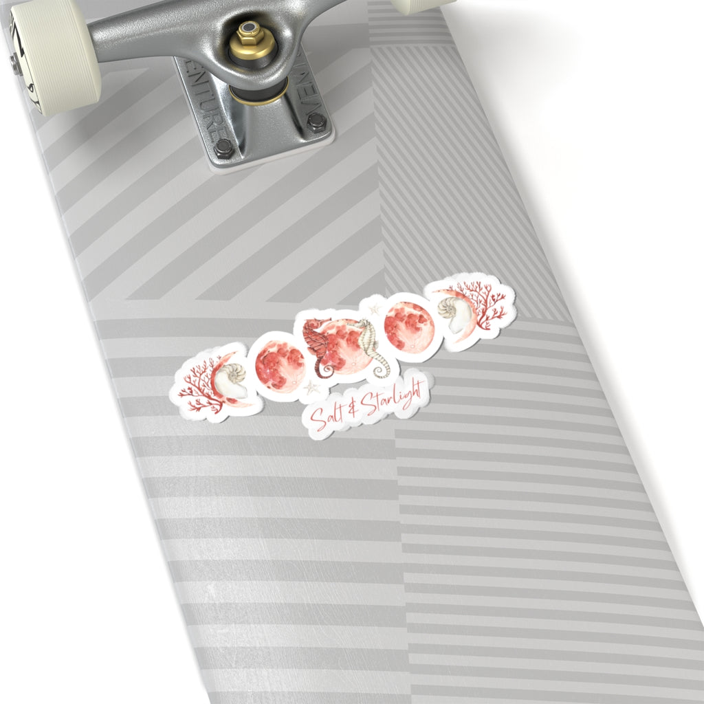 Salt & Starlight kiss-cut sticker with seahorse and coral moon phase design, shown on a longboard