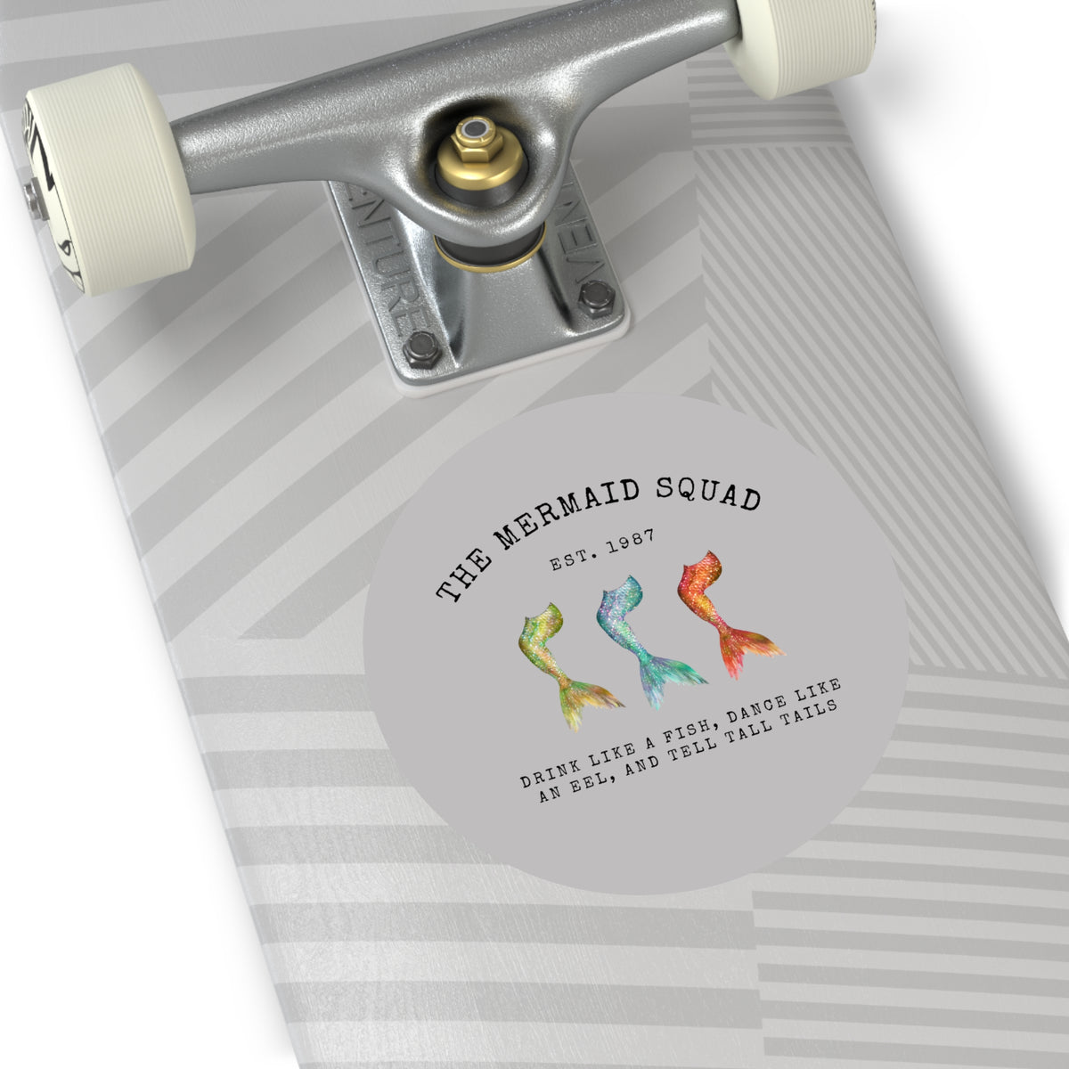 The Mermaid Squad round vinyl sticker in grey, shown on a longboard