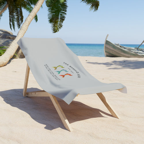The Mermaid Squad beach towel draped over a beach chair on the sand