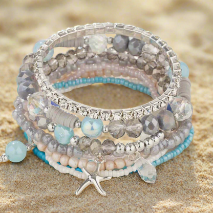 Stack of beaded bracelets with starfish charm on a white surface