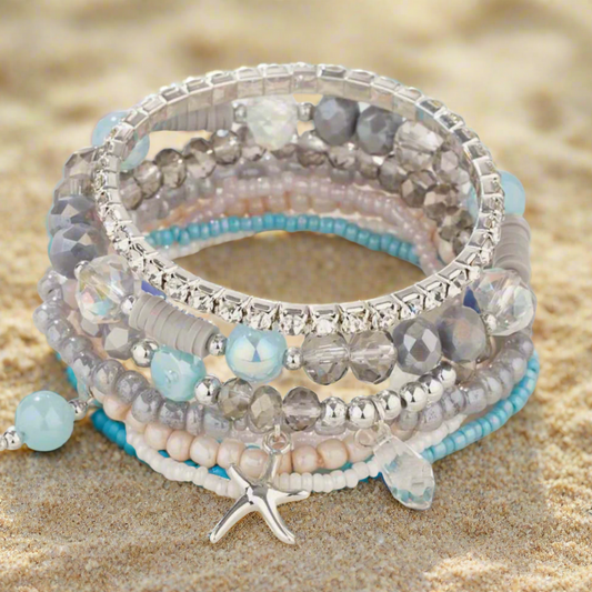 Stack of beaded bracelets with starfish charm on a white surface